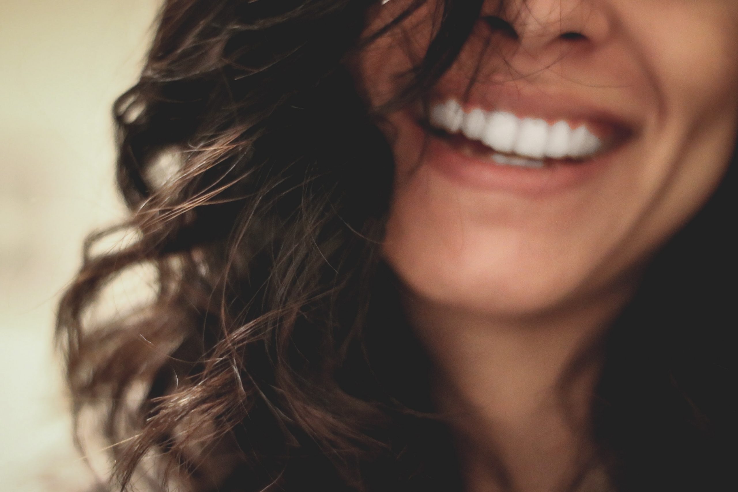 Cuidados com saúde bucal podem ser alidos na retenção de talentos. Na foto, uma mulher com pele branca e cabelos castanhos sorrindo.
